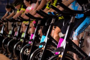 Row of bikes with people cycling watching an online class and getting fit