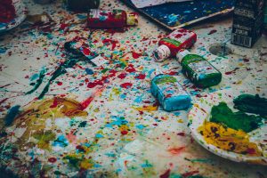 Paint bottles and paint splatter over a large white canvas for creativity for the mind